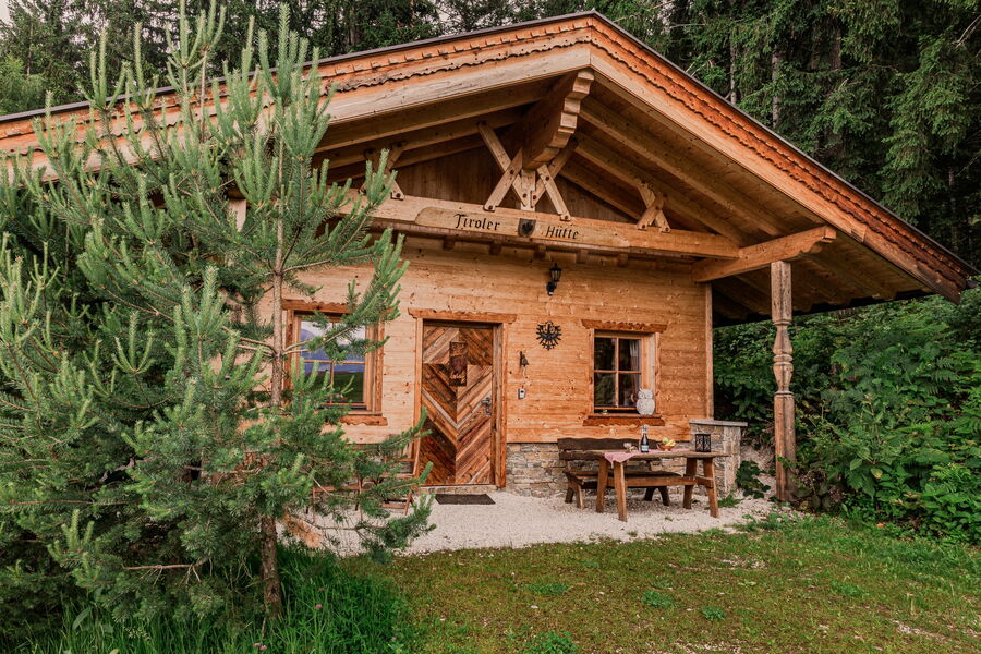 Das urige Chalet Tiroler Hütte von der Vorderansicht mit gedecktem Tisch.